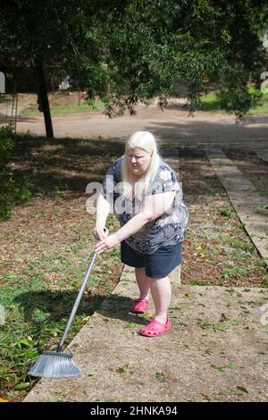 Femme nettoyant un yard Banque D'Images