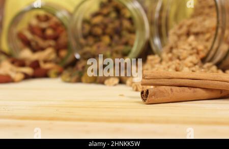 Bâtons de cannelle avec jarres de granola et noix en arrière-plan Banque D'Images