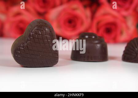 Bonbons au chocolat avec roses en arrière-plan, DOF peu profonde Focus sur le coeur chocolat Banque D'Images