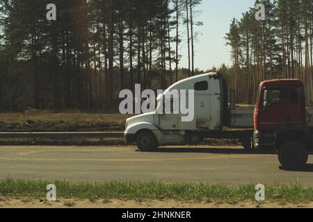 Gros camion sur le bord de la route près de la forêt. Camion blanc sur une route Banque D'Images
