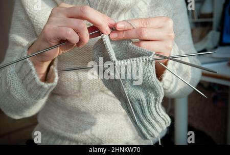 Confortable femme en tricot chaud en tricot aime le travail en tricot à la maison en hiver. Gros plan. Banque D'Images