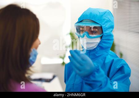 Travailleur médical dans l'équipement de protection individuelle EPI faisant le test PCR à la patiente enceinte dans le laboratoire médical, l'infirmière test femme expectant FO Banque D'Images