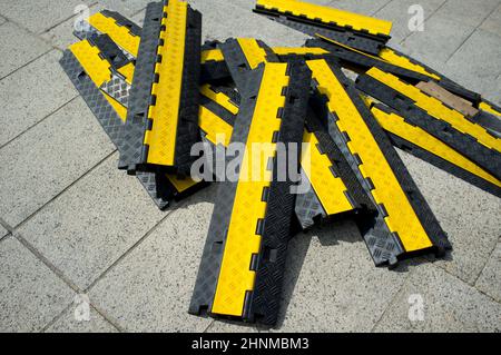 Rampe de protection en caoutchouc à deux canaux clouée au-dessus du plancher urbain historique en granit du quartier. Protecteurs de câbles robustes à côté du site de l'événement Banque D'Images