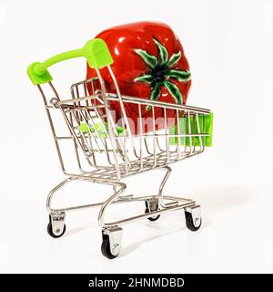 Un petit chariot de supermarché de jouet sur roues avec de la tomate rouge en elle. Banque D'Images