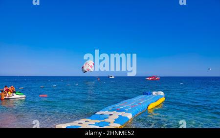 Parachute ascensionnel dans un ciel bleu près de la plage. Le parachute ascensionnel est une activité récréative populaire parmi les touristes en Turquie. Pour usage éditorial uniquement. Banque D'Images