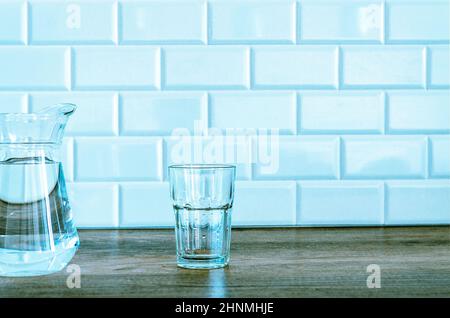 Verseuse et verre avec eau sur fond blanc. Dans la cuisine Banque D'Images