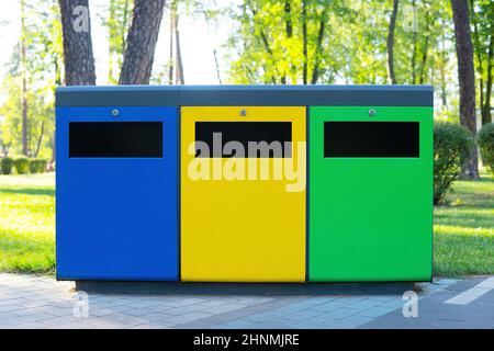 Trois poubelles de couleur pour la collecte et le tri des déchets dans le parc public. Concept de recyclage des déchets. Banque D'Images