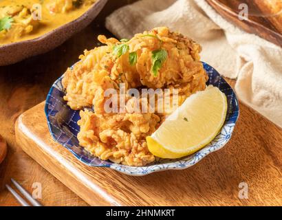 Poulet frit au Yuan coréen avec citron vert dans une assiette noire sur une assiette en bois vue du dessus de la nourriture chinoise Banque D'Images