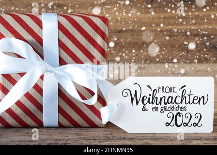 Un cadeau de Noël avec étiquette avec la calligraphie allemande Frohe Weihnachten und Ein Glueckliches 2022 signifie Joyeux Noël et Un heureux 2022. Pap. D'emballage Banque D'Images