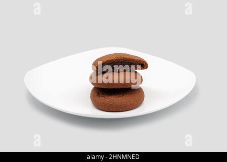 Biscuits aux flocons d'avoine avec garniture au chocolat. Sur une plaque blanche. Banque D'Images