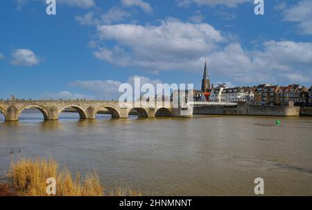 Maastricht (Sint Servaasbrug), pays-Bas - février 13. 2022: Vue sur la rivière maas sur le vieux pont piétonnier en pierre calcaire voûtée contre le ciel bleu d'hiver Banque D'Images