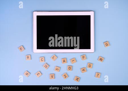 quelques lettres de l'alphabet sur des blocs de bois et une tablette sur une surface colorée Banque D'Images