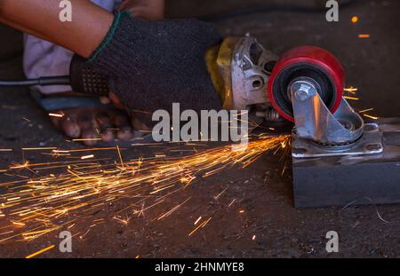 Travailleur industriel utilisant une meuleuse d'angle coupant le métal. Employé travaillant avec une meuleuse d'angle et présentant des étincelles d'orange. Outil pour couper et meuler l'acier. Sécurité sur le lieu de travail industriel. Industrie des usines de métaux. Banque D'Images