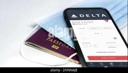 Téléphone avec l'application Delta Airlines à l'écran, au-dessus d'un masque chirurgical et d'un passeport Banque D'Images