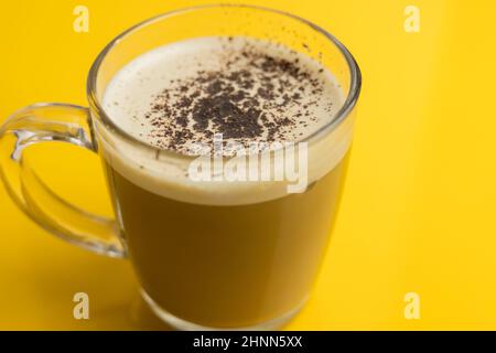 Belle mousse de lait de café. Café au lait dans un verre transparent sur fond jaune, vue du dessus. Banque D'Images