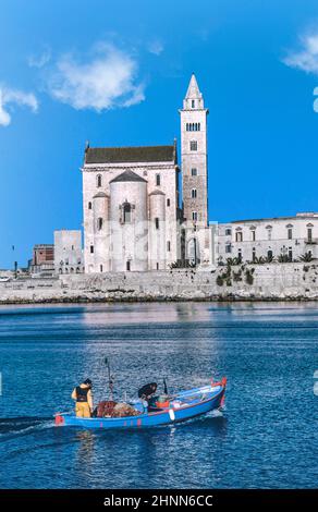 cathédrale sur la mer à Trani avec un bateau de pêche passant Banque D'Images