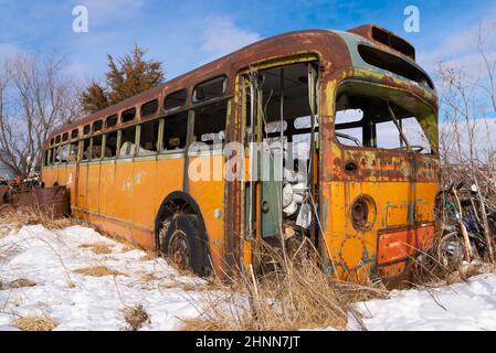 Bus abandonné rouillé dans un champ couvert de neige. Banque D'Images