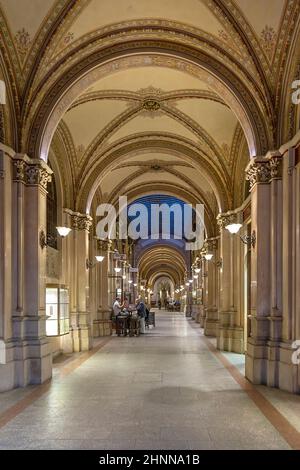 La nuit, les gens s'assoient dans un restaurant le long des portiques illuminés (arcades) dans la belle capitale architecturale et majestueuse de l'Autriche Banque D'Images