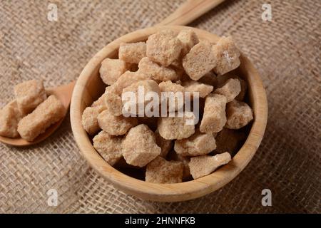 Cubes de sucre brun Demerara dans un bol en bois.Également appelé morceaux de sucre.Sucrose produit de couleur marron caractéristique en raison de la présence de mélasse Banque D'Images