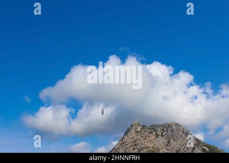 Silhouette de parapente survolant la vallée de montagne brumeuse dans de belles couleurs chaudes de coucher de soleil - sport, fonds d'écran actifs plein de liberté. Banque D'Images