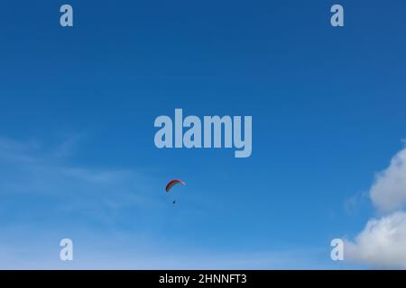 Silhouette de parapente survolant la vallée de montagne brumeuse dans de belles couleurs chaudes de coucher de soleil - sport, fonds d'écran actifs plein de liberté. Banque D'Images