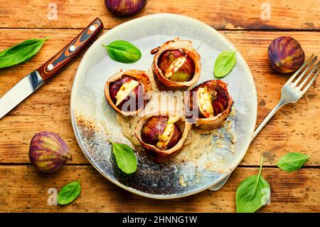 Figues enrobées de bacon rôti farci de fromage de chèvre. Figues cuites au four Banque D'Images