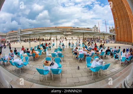 Vue sur la place Saint-Marc avec campanile et basilique avec les touristes profitant de la vue dans un café en plein air sur la place Saint-Marc à Venise, Italie Banque D'Images