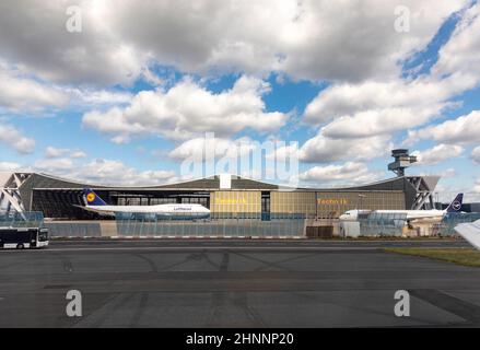 salle de maintenance lufthansa en construction papillon avec parking Boeing 747 et un Airbus devant et passage de l'équipage de bus Banque D'Images