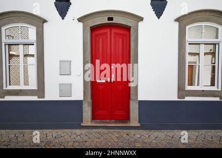 Porte laquée rouge à la façade blanchie à la chaux, fenêtres en miroir de maison de ville néoclassique. Tavira-Portugal-111 Banque D'Images