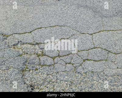 Vue détaillée sur les surfaces asphaltées de différentes rues et routes présentant des fissures en gros plan Banque D'Images