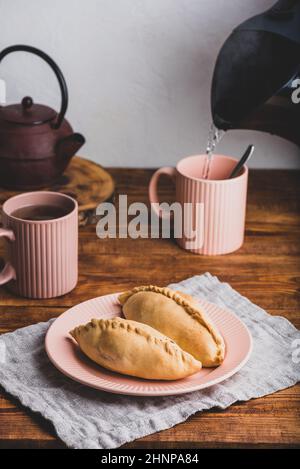 Deux mini-chaussons de chou faits maison sur l'assiette et tasses avec Thé Banque D'Images