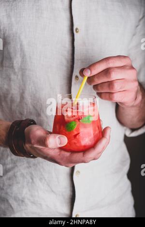 Verre de cocktail de pastèque avec gin et soda dans les mains Banque D'Images