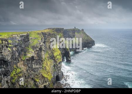 Touristes visitant les falaises de Moher avec Moher Tower sur une distance, Irlande Banque D'Images