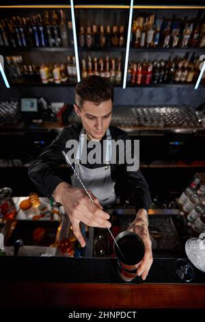 Barman mélange cocktail dans shaker avec cuillère Banque D'Images