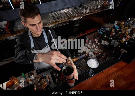 Barman mélange cocktail dans shaker avec cuillère Banque D'Images