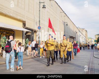 Moscou. Russie. 9 mai 2021. Un groupe d'hommes sous la forme de soldats soviétiques avec une bannière rouge est en marche dans la rue de la ville. Procession en l'honneur du jour de la victoire dans la Grande Guerre patriotique. Banque D'Images