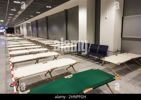 les lits de camp vides sont debout rangée par rangée dans le terminal de l'aéroport Banque D'Images