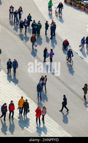 les gens qui marchent dans la rue avec de longues ombres Banque D'Images
