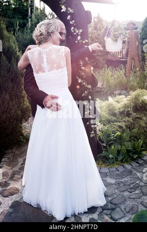 Bride and Groom posant dans le jardin sous le soleil d'après-midi Banque D'Images