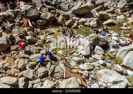 Les touristes rafraîchissent leurs jambes dans le lac de la chute d'eau inférieure de Yosemite Banque D'Images