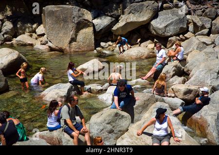 Les touristes rafraîchissent leurs jambes dans le lac de la chute d'eau inférieure de Yosemite Banque D'Images