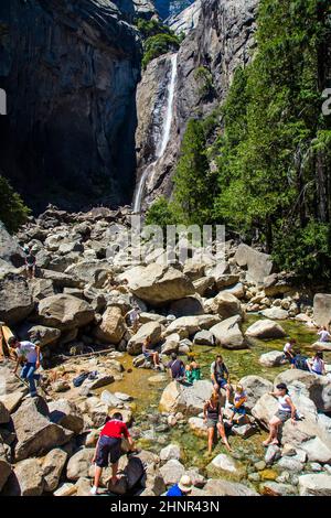 Les touristes rafraîchissent leurs jambes dans le lac de la chute d'eau inférieure de Yosemite Banque D'Images