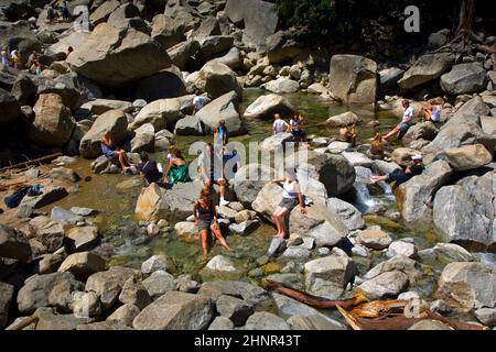 Les touristes rafraîchissent leurs jambes dans le lac de la chute d'eau inférieure de Yosemite Banque D'Images