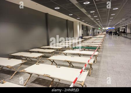 les lits de camp vides sont debout rangée par rangée dans le terminal de l'aéroport Banque D'Images