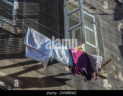 femme avec foulard fixe le lavage sur une ligne de lavage en face de la façade Banque D'Images