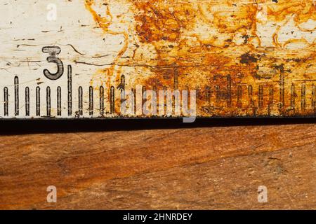 Ancienne règle rouillée avec numéros noirs sur une table en bois en état de marche. Ruban de mesure vintage gros plan. Milieu industriel. Atelier de menuiserie Banque D'Images