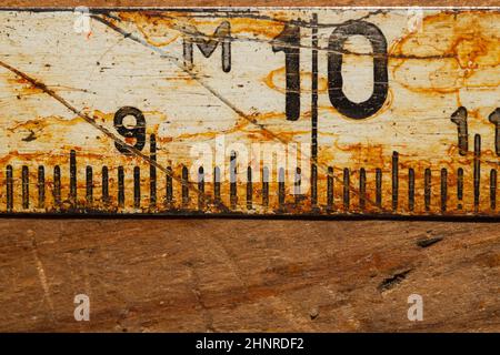 Ancienne règle rouillée avec numéros noirs sur une table en bois en état de marche. Ruban de mesure vintage gros plan. Milieu industriel. Atelier de menuiserie Banque D'Images