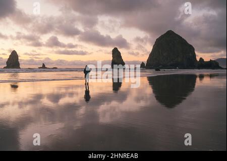 Femme regardant le coucher du soleil à Cannon Beach sur la côte de l'Oregon Banque D'Images