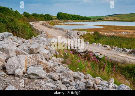 La grande lagune de décantation à Cavendish Mill est une œuvre de spath fluor, près de Stoney Middleton, avec de grands blocs de calcaire au premier plan. Banque D'Images