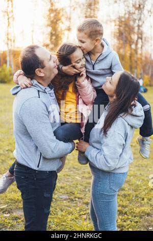 Une famille de quatre heureux passant leur temps libre dans le parc, le frère embrassant sa sœur sur le front. . De bonnes vacances en famille. Jeux pour enfants Banque D'Images